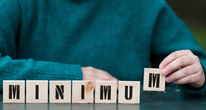 A user placing wooden blocks with characters showing minimum to represent - What is the Bare Minimum for Forex Trading?